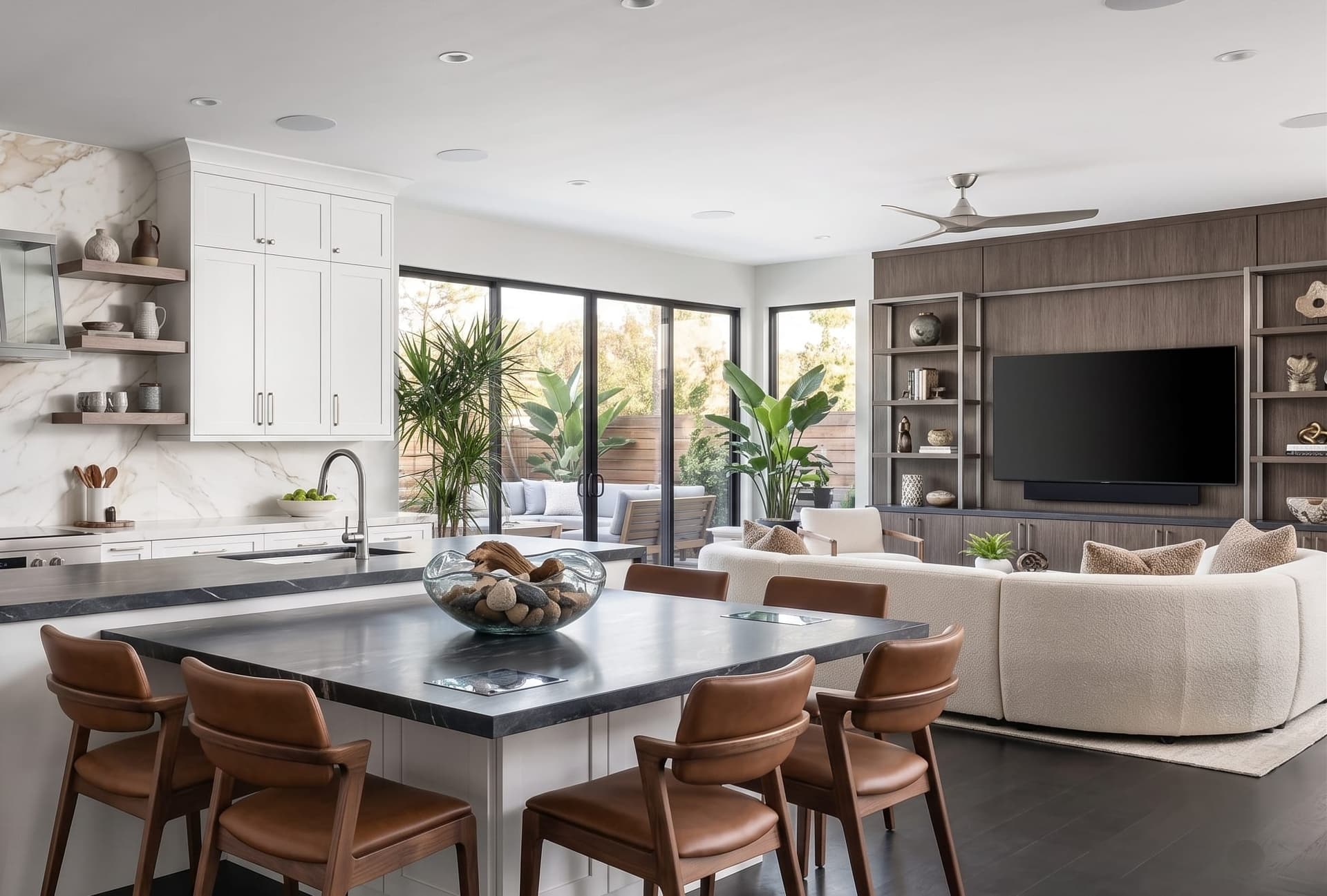 Open-plan kitchen and living area with a wall-mounted television, soundbar and in-ceiling speakers, the kind of layout we design and calibrate systems for