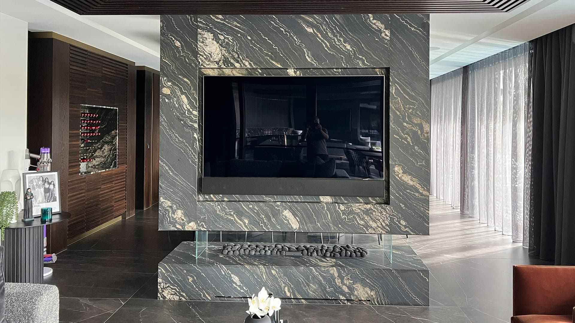 Television recessed into a book-matched marble feature wall with a concealed fireplace below, a full feature-wall installation
