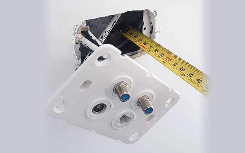 TV wall plate removed to show the wall cavity and coaxial cabling behind it