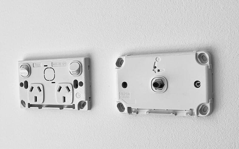 Rear of a TV wall plate and a power outlet plate showing the terminals