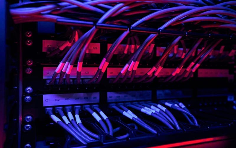 Network rack of patch leads lit by blue and red equipment indicator lights