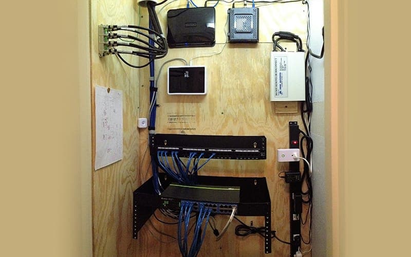 Network equipment mounted on a plywood backboard with a patch panel and cable management