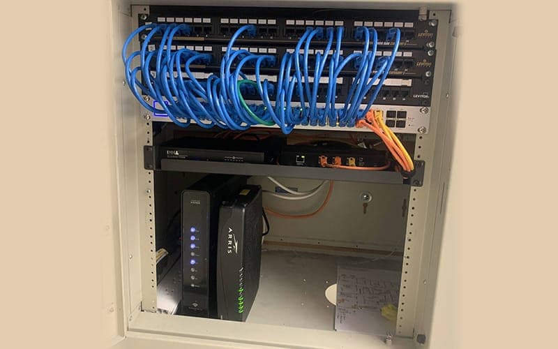 Home comms cabinet with a Cat6 patch panel above and a modem router below