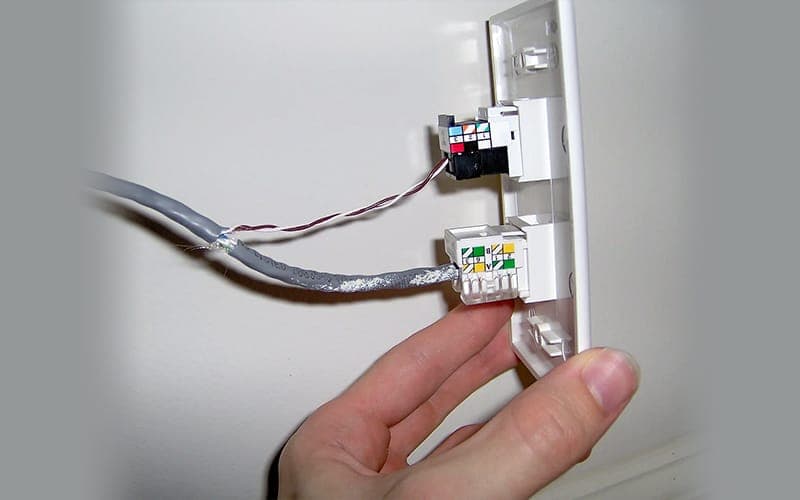 Cat6 cable being punched down into a keystone jack on a data point wall plate