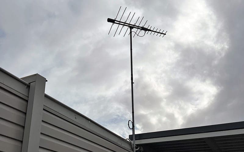 Digital TV antenna mounted on a mast above the gutter line of a house