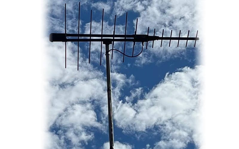 Log-periodic digital TV antenna mounted on a mast against a cloudy sky