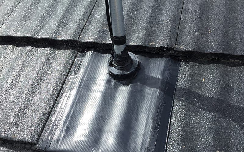 Antenna mast base sealed to a slate roof with a weatherproof flashing boot