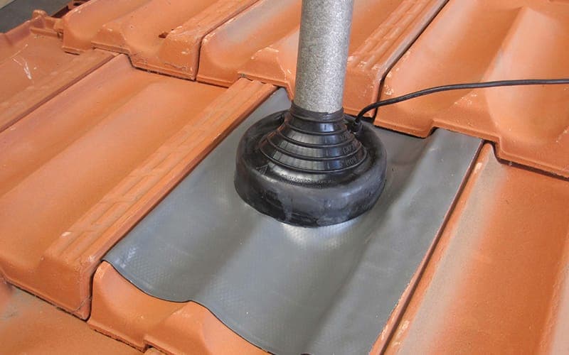 Antenna mast base flashed and sealed into a terracotta tiled roof