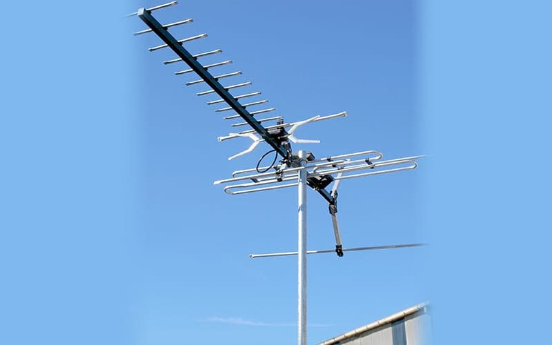 Combined UHF and VHF digital TV antenna mounted on a mast against a blue sky