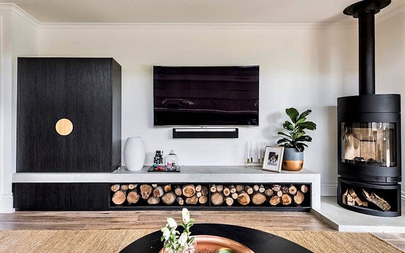 Wall-mounted TV with a soundbar above a timber media unit beside a freestanding fireplace