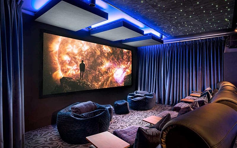 Dedicated home theatre with a projector screen, bean-bag seating and blue LED ceiling detail