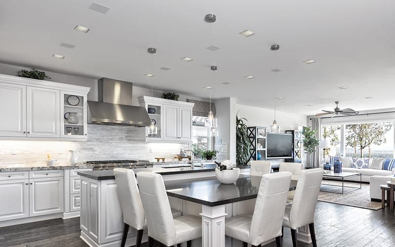 Open-plan kitchen and living area with a wall-mounted TV and in-ceiling speakers