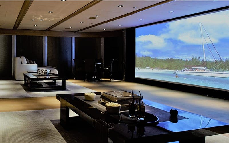 Home cinema lounge with a large projection screen and dark timber-lined walls