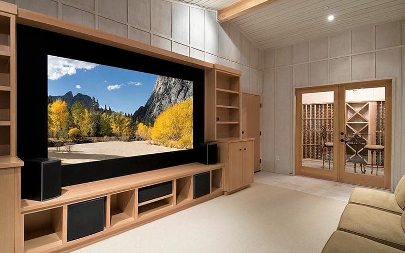 Home theatre wall with a wide screen set into timber joinery, speakers and a subwoofer below