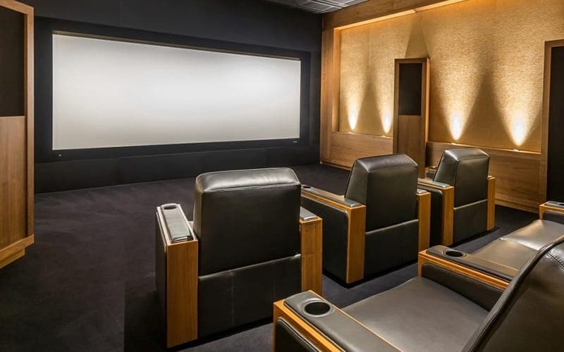 Home cinema with acoustic wall panels, wall sconces and tiered leather recliner seating