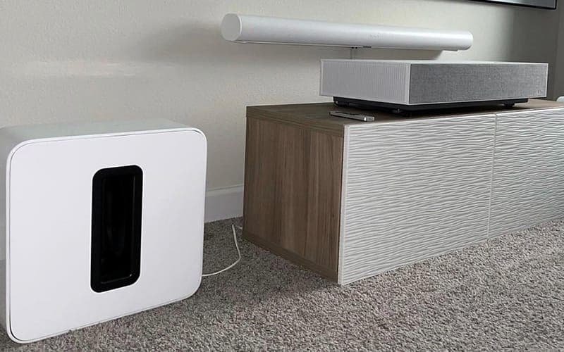 Ultra short throw projector on a media cabinet with a wireless subwoofer beside it
