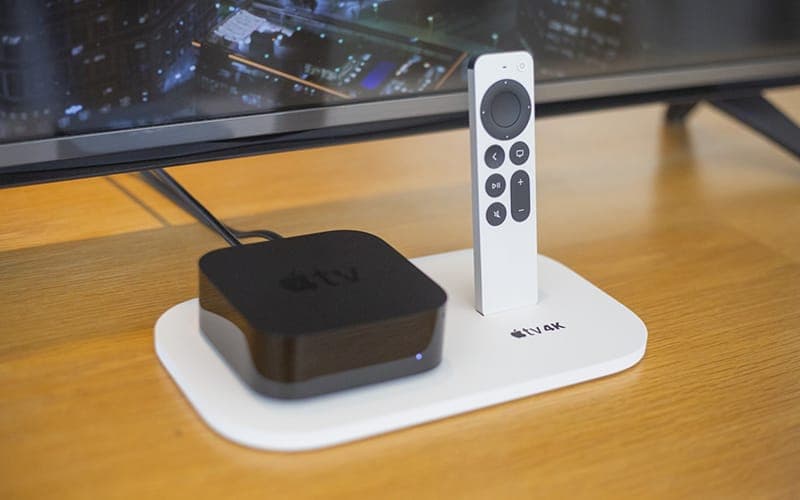 Apple TV 4K box and remote on a desk in front of a television