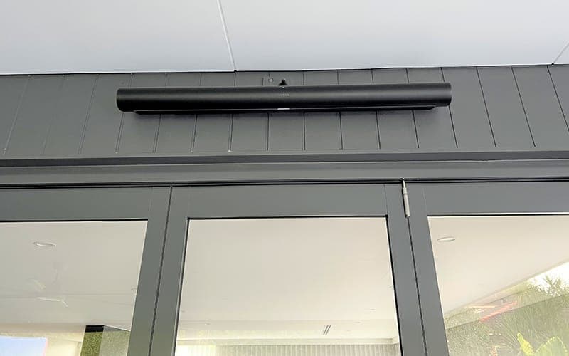 Outdoor speaker and radiant strip heater mounted under an alfresco eave above bi-fold doors