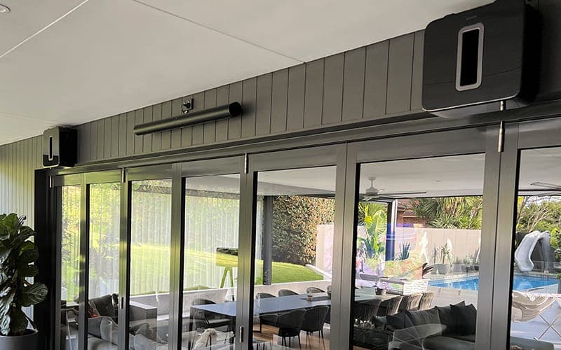 Outdoor speakers and a strip heater mounted above stacking glass doors onto a pool area