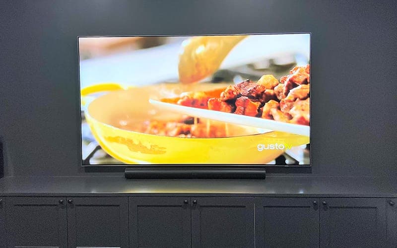 Wall-mounted TV above dark joinery with a soundbar mounted directly beneath the screen