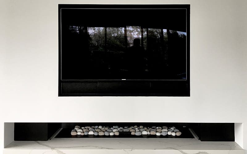 TV recessed into a wall above a media niche with lighting beneath
