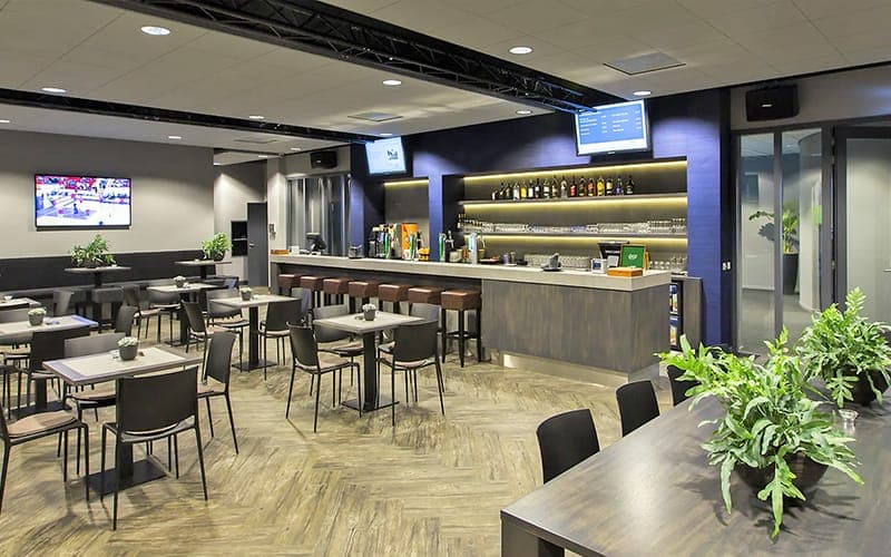 Commercial bar and dining area with ceiling speakers and wall-mounted screens