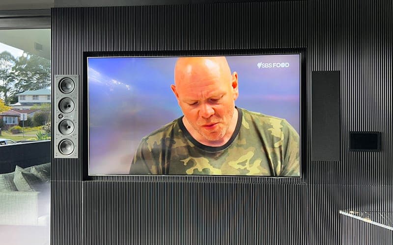 TV on a fluted black feature wall with in-wall column speakers either side