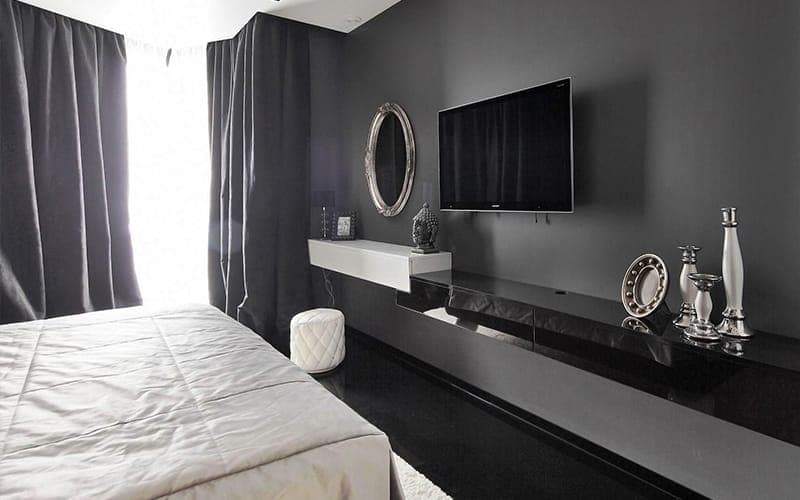 TV wall mounted above a floating cabinet on a charcoal bedroom wall, cables concealed in the wall