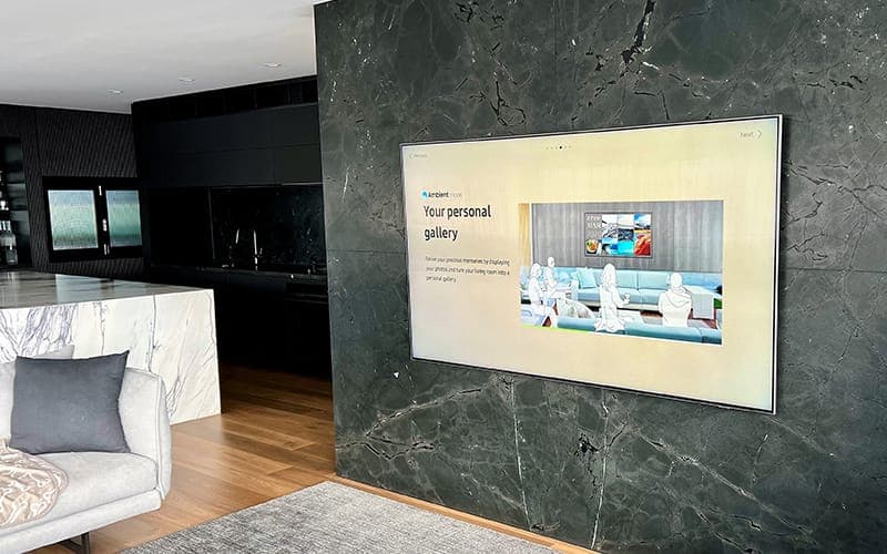Frame-style TV on a dark marble feature wall in an open-plan kitchen and living area
