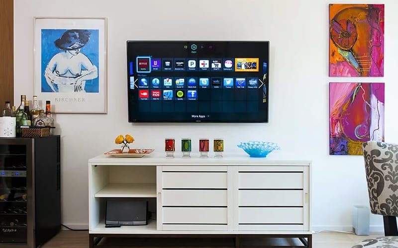Smart TV wall mounted above a sideboard between framed artworks