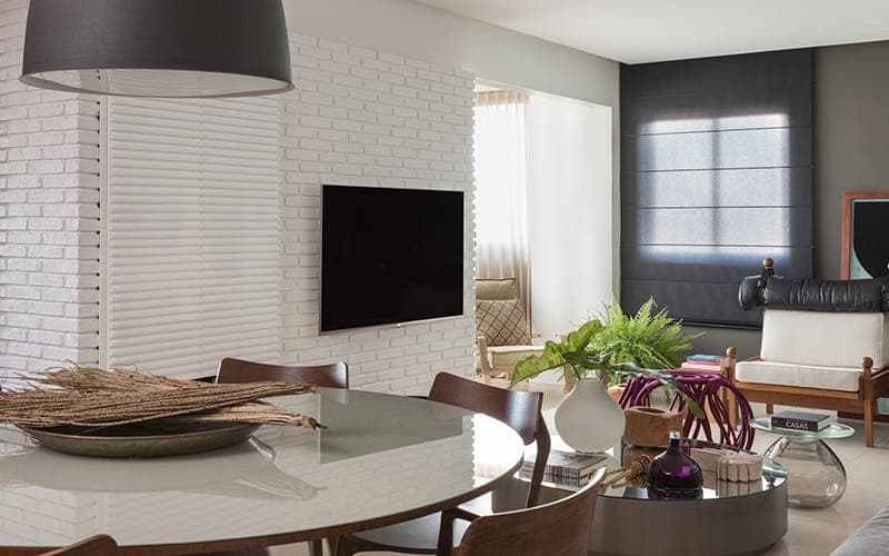 TV mounted on a white brick feature wall in an open-plan dining and living area