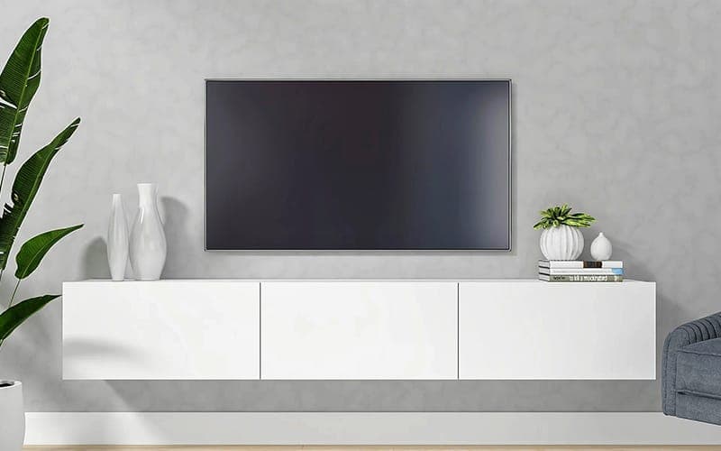 Large TV wall mounted above a white floating cabinet on a grey wall