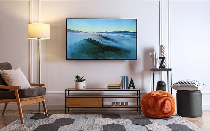 TV wall mounted above a slim black media console in a living room