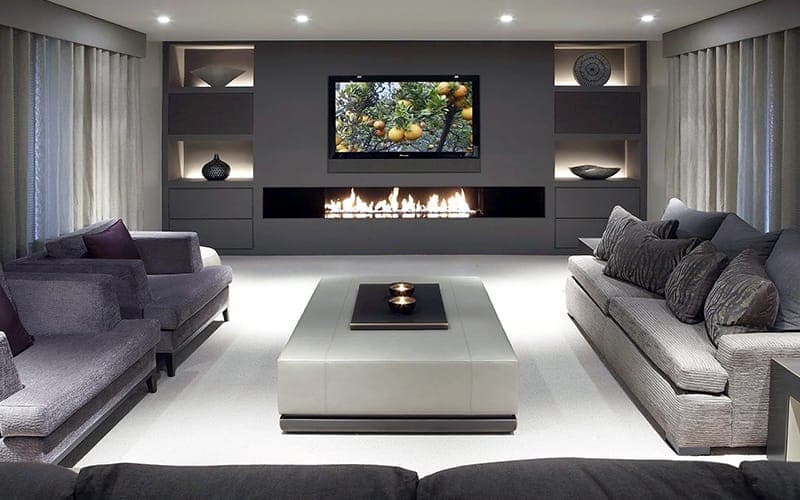TV recessed into grey joinery above a linear fireplace with lit display niches