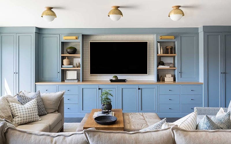 TV set into blue-grey built-in cabinetry with a timber surround