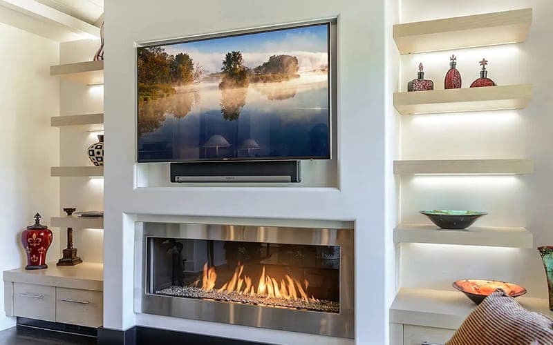 TV recessed above a gas fireplace between LED-lit display niches