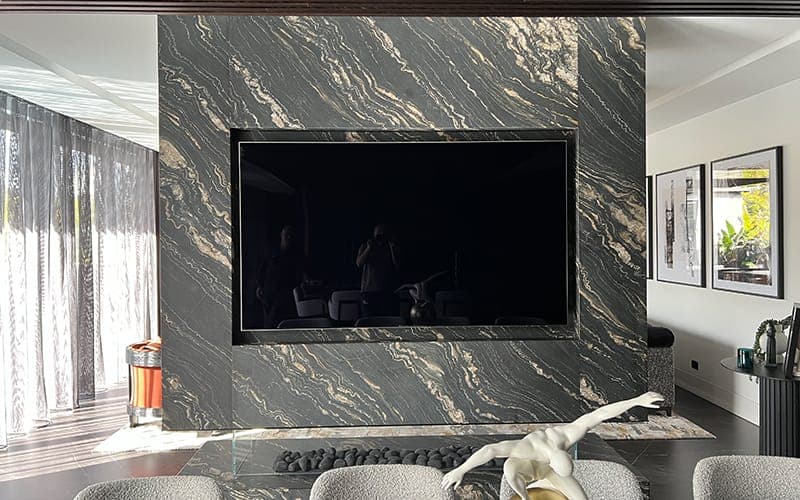 Large TV recessed into a book-matched marble feature wall in an open-plan living area
