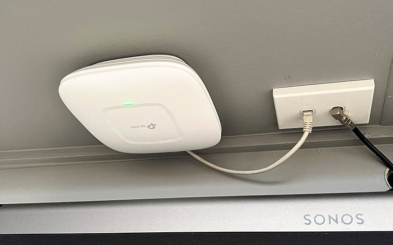 Wi-Fi access point mounted on a wall beside a data point and power outlet