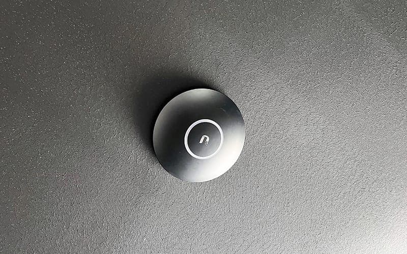 Wi-Fi access point mounted on a dark textured ceiling